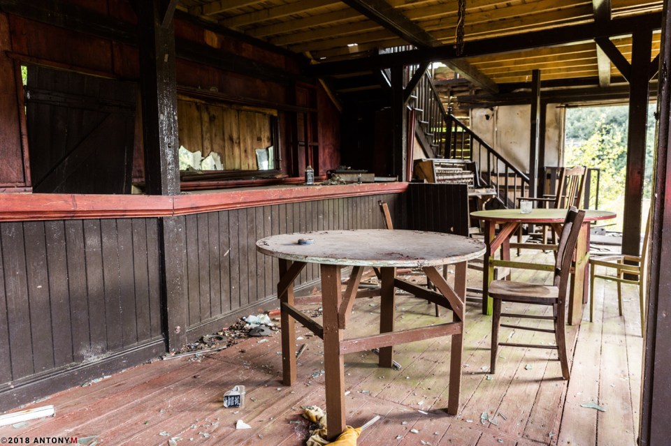 A deserted saloon bar is littered with debris and broken glass