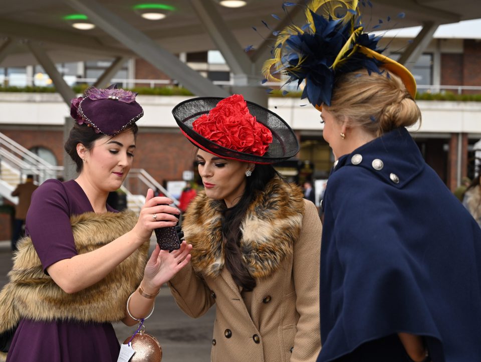  Racegoers gather round a phone - perhaps to see if windy photos pass the test