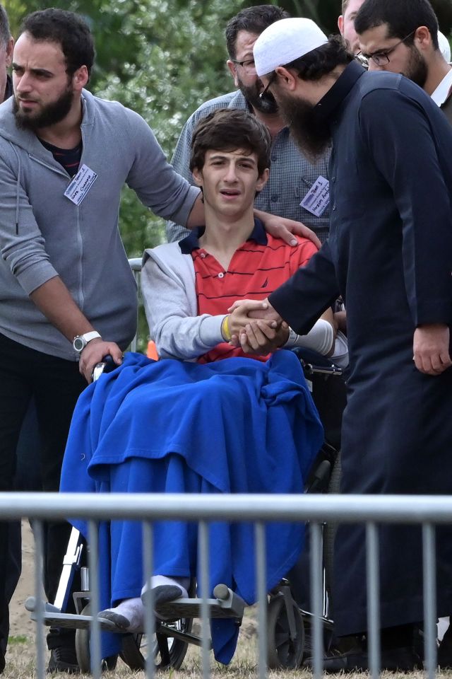  Injured Zaid Mustafa is comforted by friends and family at the funeral of his brother and father