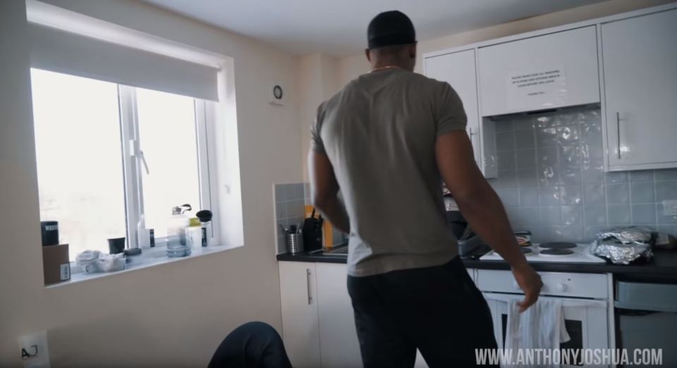  Anthony Joshua leads the cameraman to the kitchen where a tub of butter sits on the small electric hob