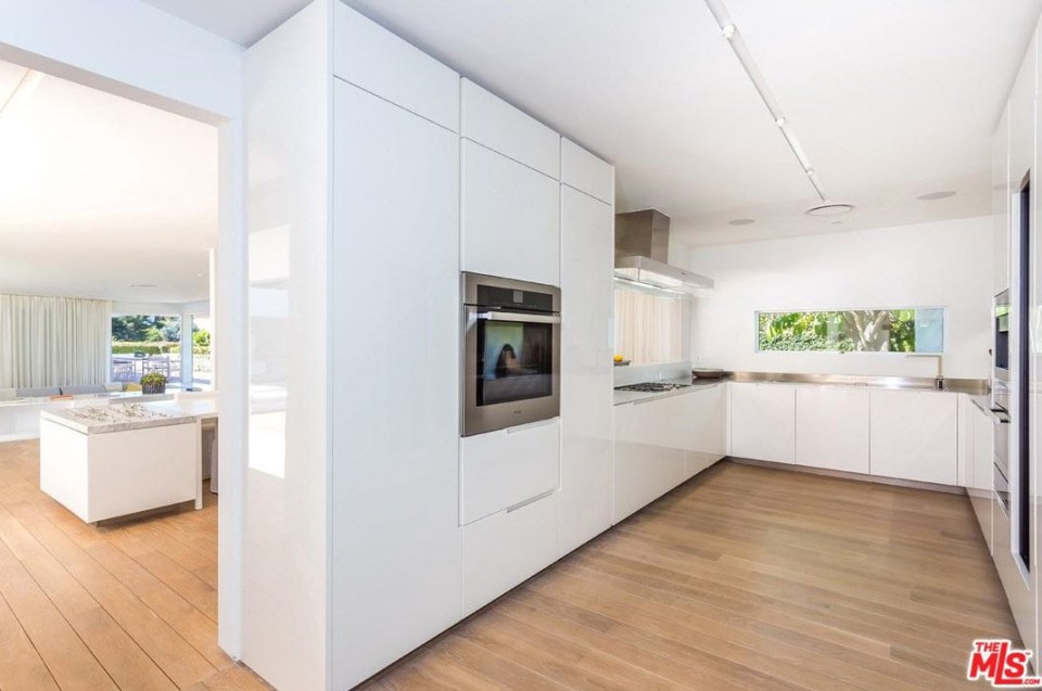  The white, bright kitchen is next, with a thin window looking out to the garden