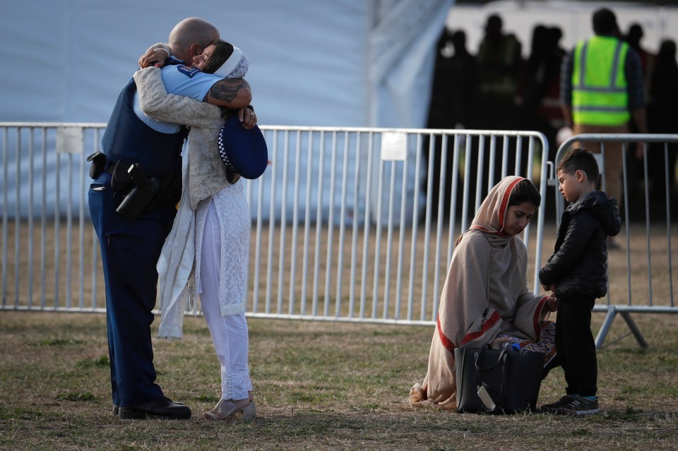 A family member hugs a policeman during a burial ceremony for victims of the mosque attacks, at the Memorial Park Cemetery in Christchurch