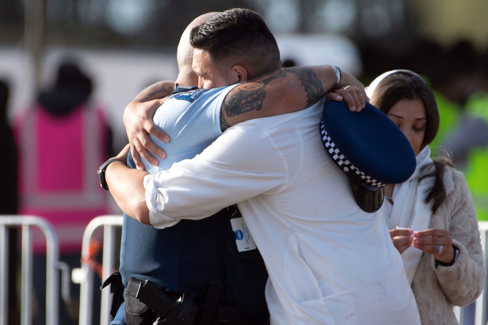 A police officer hugs a Muslim mourner during a funeral ceremony at the Memorial Park in Christchurch