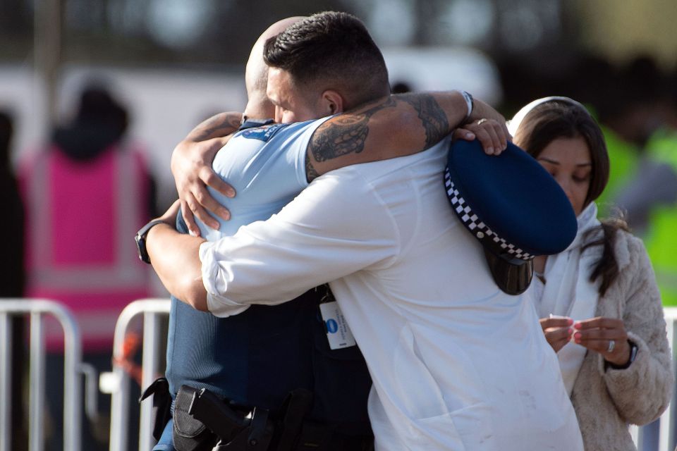  A police officer hugs a Muslim mourner during a funeral ceremony at the Memorial Park in Christchurch