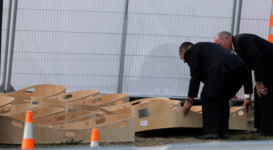  Men lay an empty coffin on the ground following a burial ceremony at Memorial Park Cemetery in Christchurch