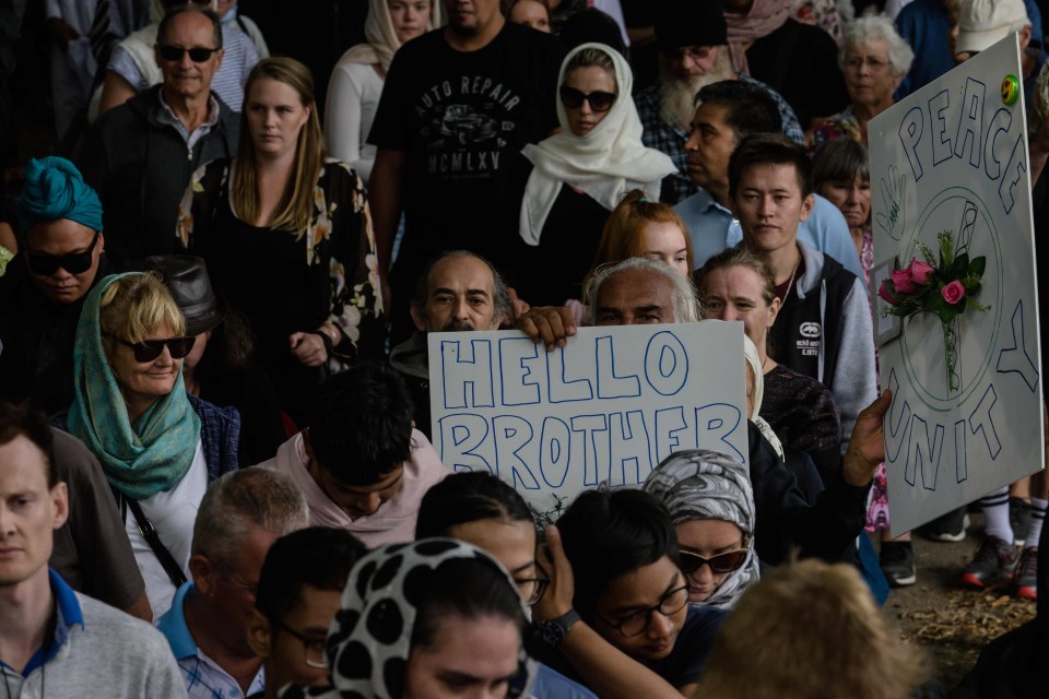 People hold placards after a Muslim prayer service and two minute’s silence for twin mosque massacre victims in a park near the Al Noor Mosque in Christchurch