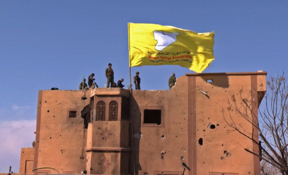  The US-backed SDF raise their flag atop a building in ISIS's last bastion of Baghouz