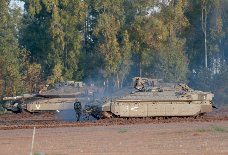  Israeli soldiers work next to their tanks near the Israel-Gaza border