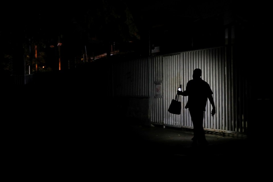  A resident uses light from a cellphone as he walks along a street