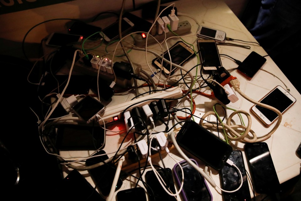  Phones are seen on a table as they are charged by a generator at a public square