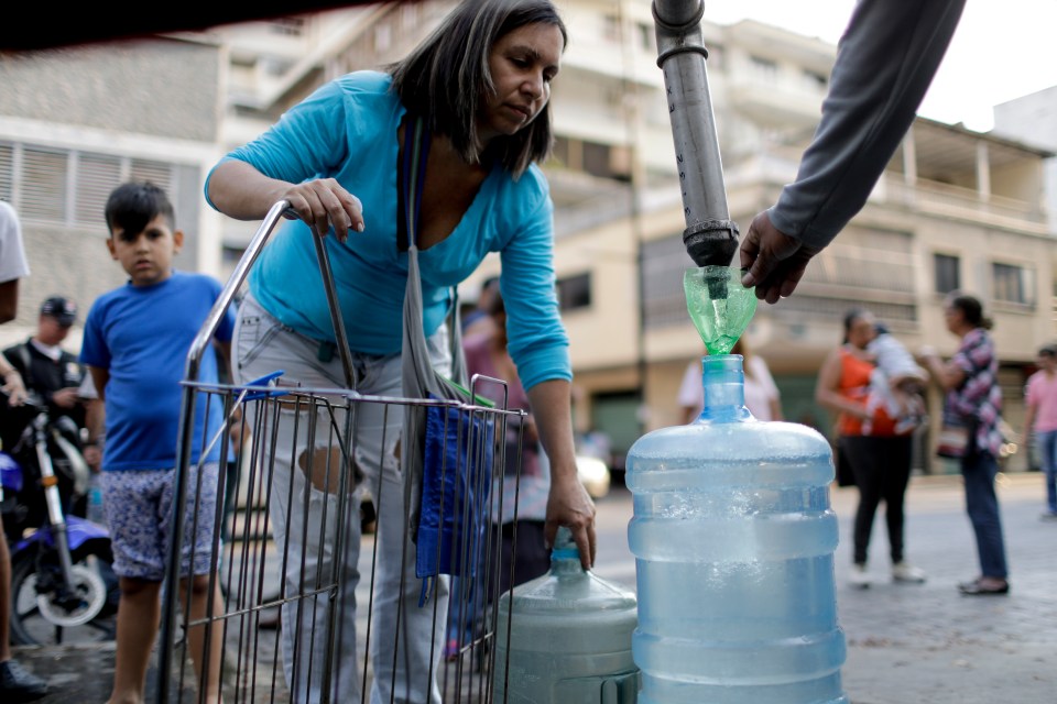  A woman fills a container with water from a truck