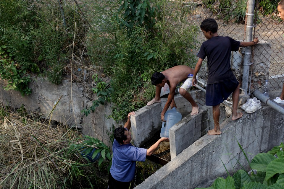  A man collects water from a stream to bring home to his family