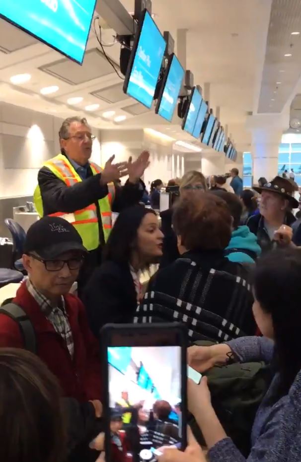  A member of staff attempts to direct passengers at Toronto Airport following the collapse of Wow Air