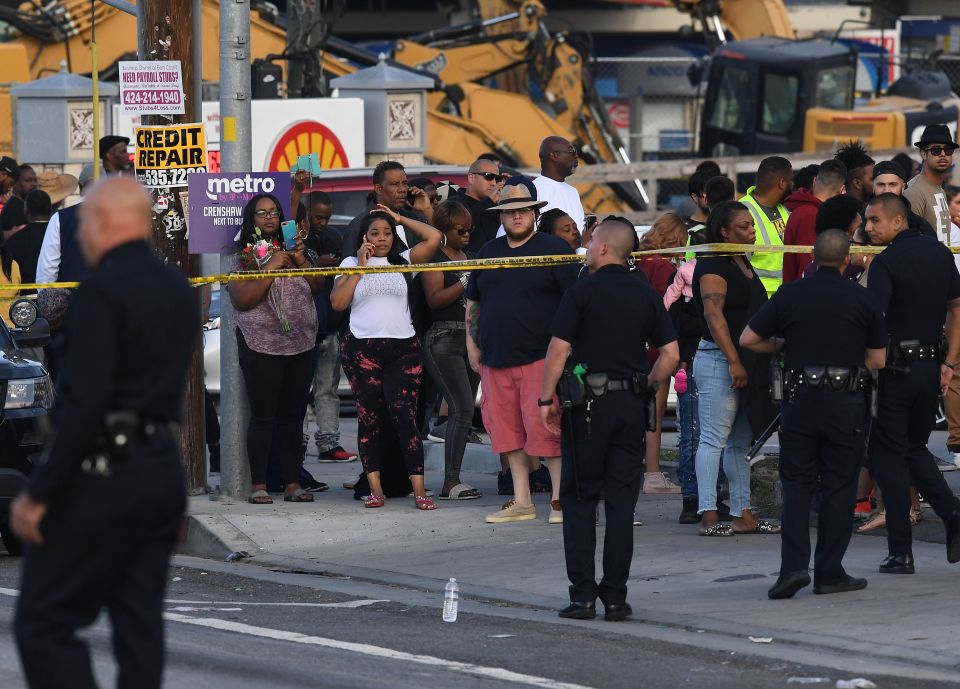  Onlookers gather at the scene of the deadly shooting as police cordon off the area