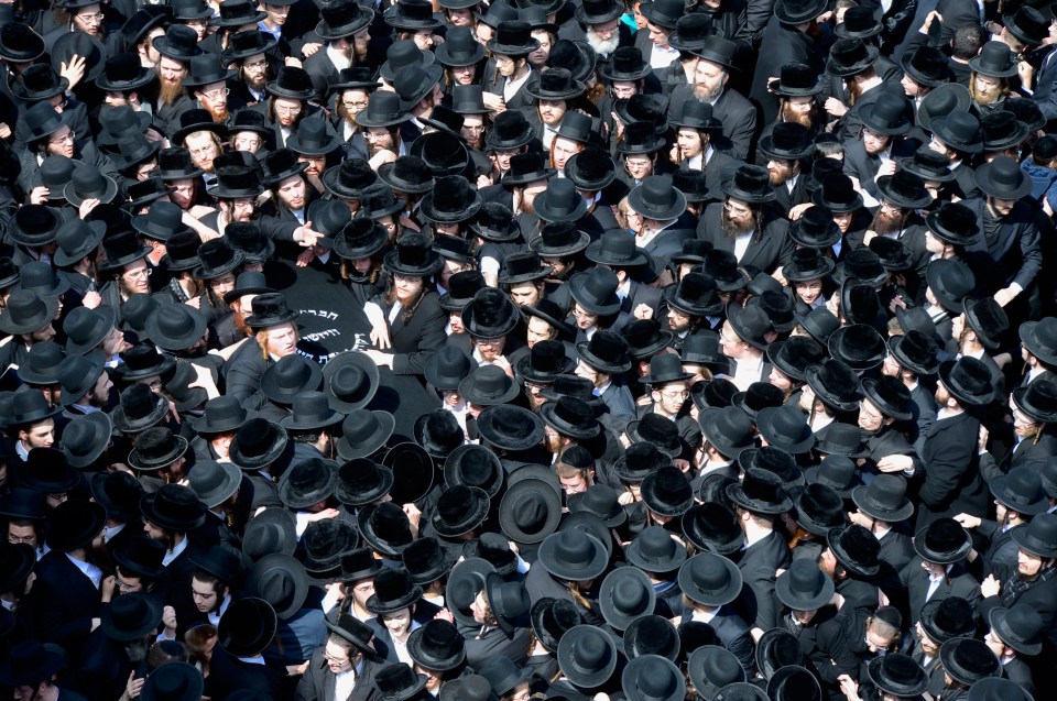  Mourners reach to touch the coffin carrying Yisroel Avrohom Portugal, the Skulener Rebbe