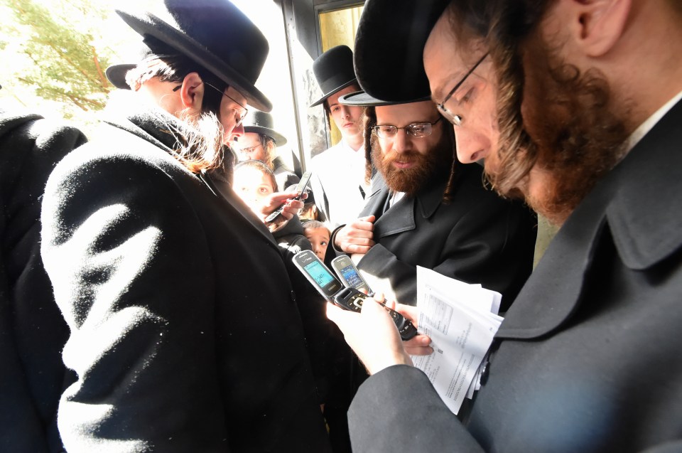  Mourners check their phones after they were banned from taking part in the ritual while carrying them