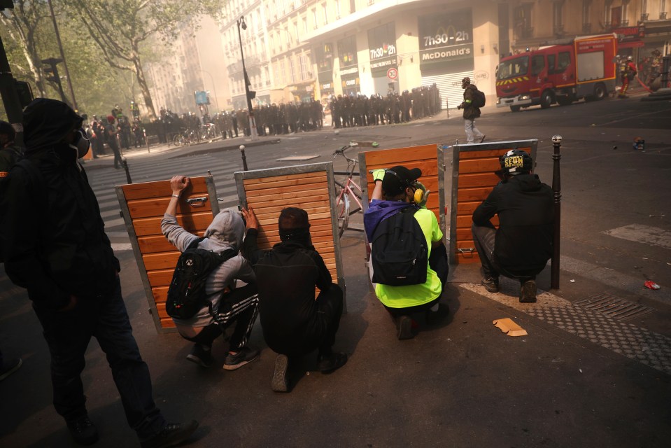  Protesters take shelter behind wooden panels during clashes with police