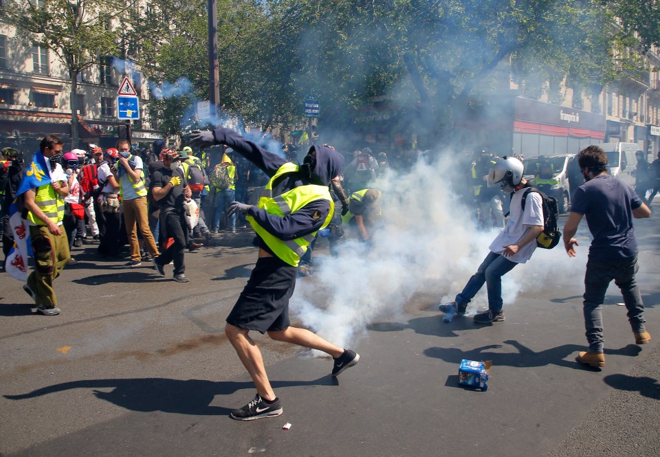  A Yellow Vest protester through a tear gas canister back to police