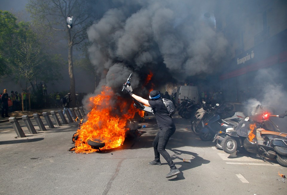  A protester throws a scooter onto a pile of burning motorbikes in Paris today