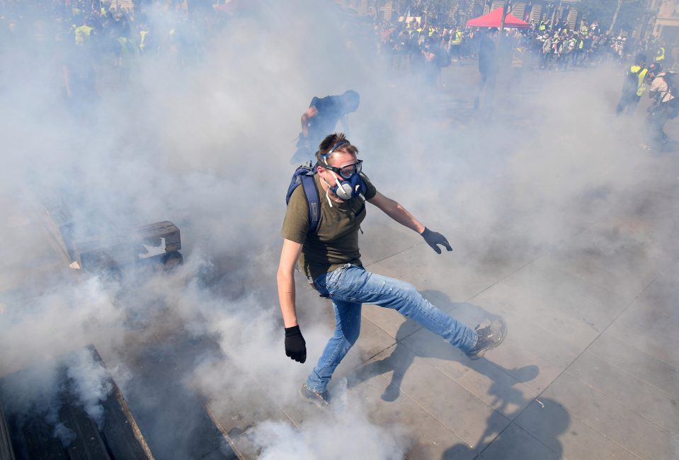  A yellow vest demonstrator walks through smoke canisters in Paris