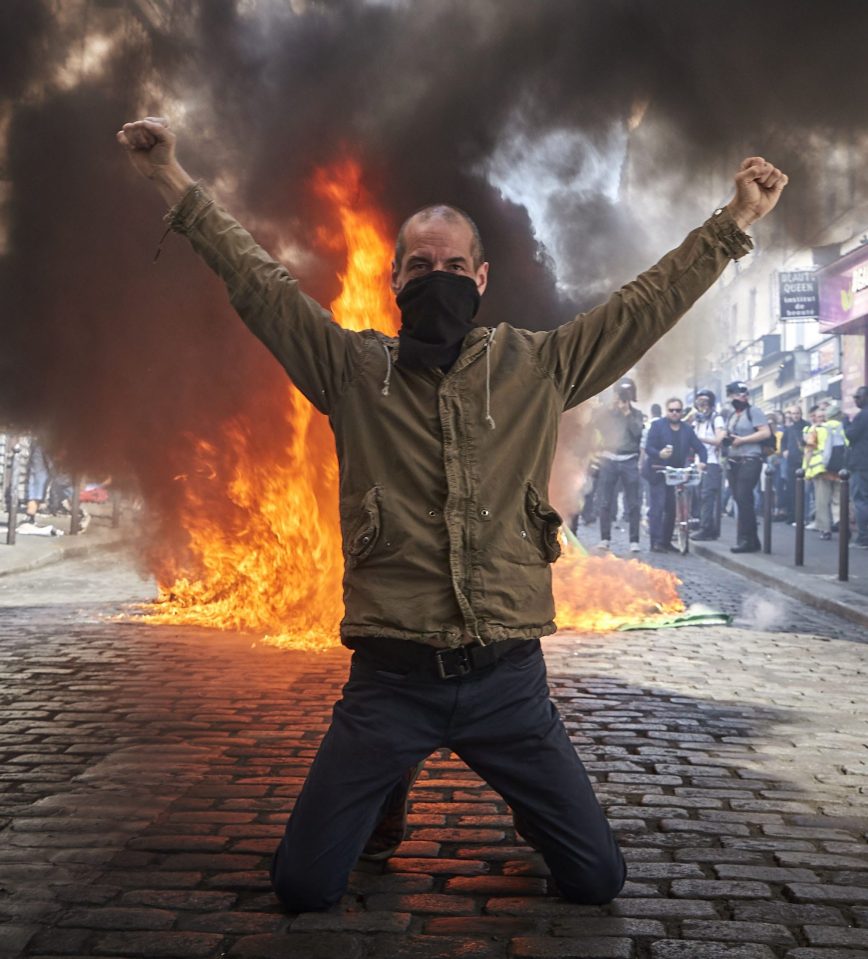  A Gilet Jaune in front of a burning barricade