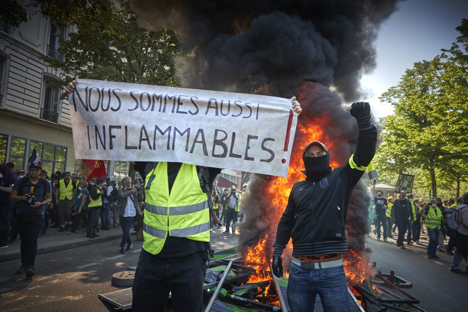  A Yellow Vest holds a sign that reads 'we can also burn' in French