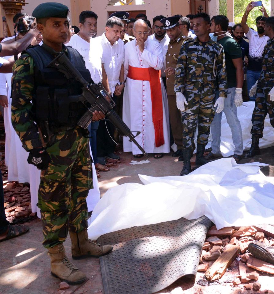  Onlookers including priests gather round a body which has been covered with a white sheet at the church in Sri Lanka