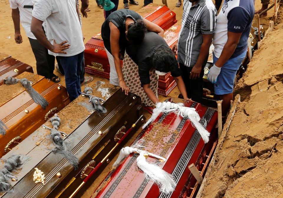  Coffins are laid in the ground during a mass burial for victims at a cemetery near St Sebastian's Church in Negombo