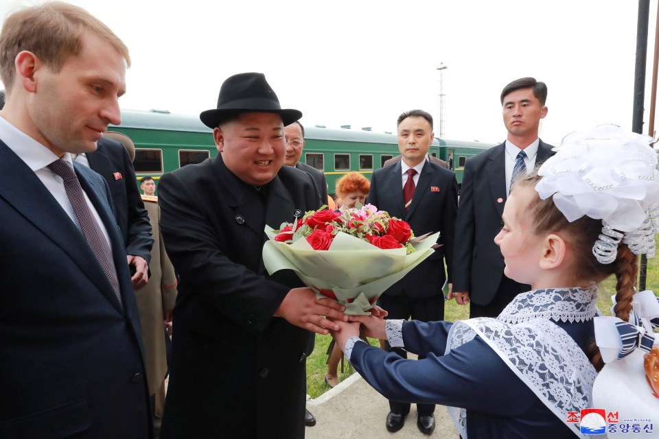  The despot is handed a bouquet of flowers by a Russian girl