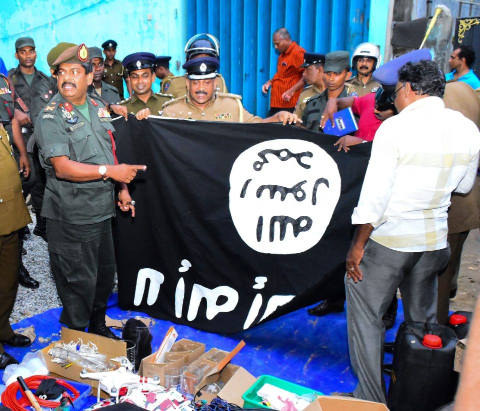  Military personnel display an ISIS banner after their raid on the safe-house near the eastern town of Kalmunai