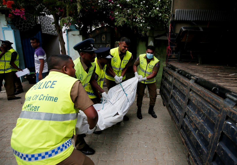  Police officers remove a body at the site of the overnight gun battle