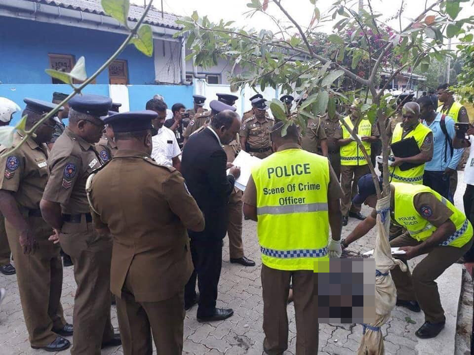  Security officers and officials inspect a body at the site of the gun battle