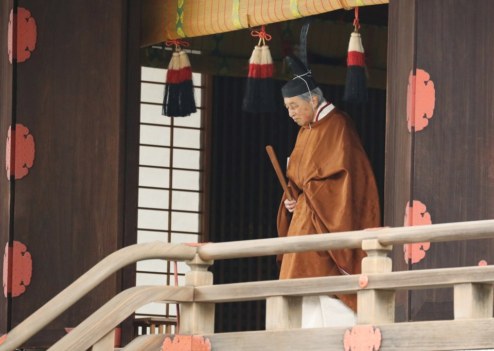 Stepping down: Akihito wearing an orange robe and black headdress, entering the Shrine of Kashikodokoro at the Imperial Palace