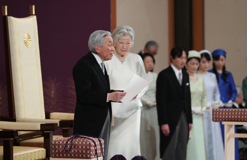 Emperor Akihito, flanked by Empress Michiko, delivers a speech