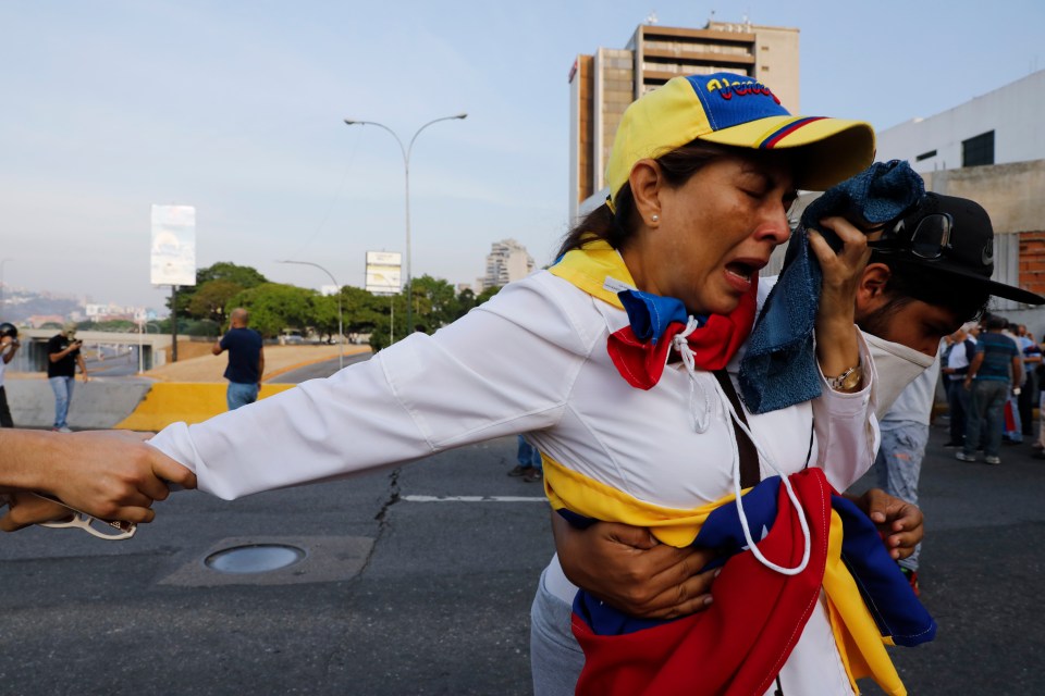  A Guaido supporter wipes her eyes after tear gas was fired by government troops