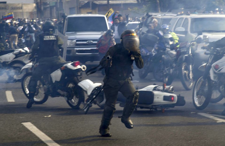  Members of the Bolivarian National Guard loyal to Nicolas Maduro run under a cloud of tear gas after being repelled by forces backing Juan Guaido