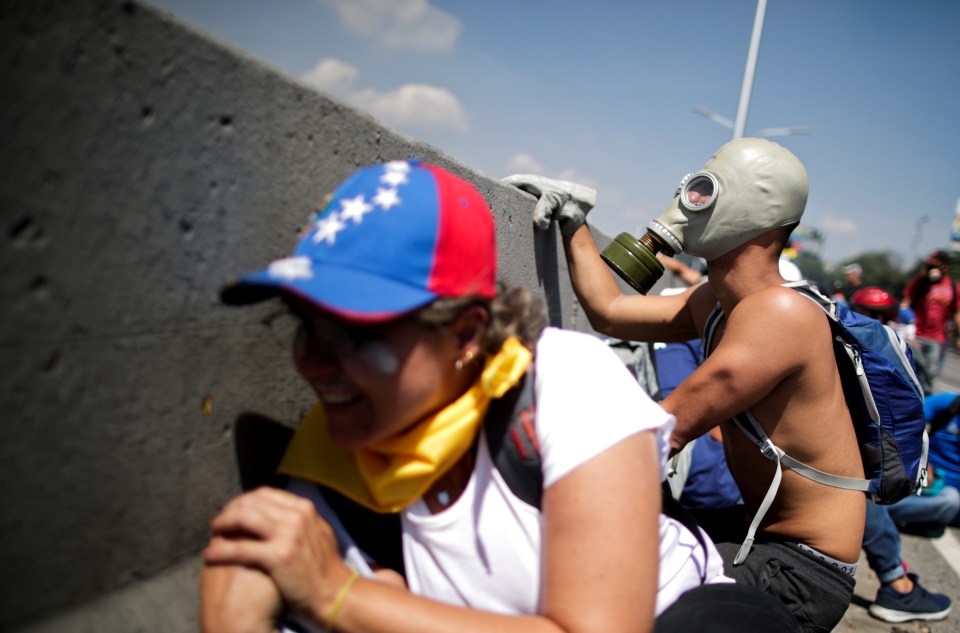  An opposition demonstrator peers over a concrete barrier