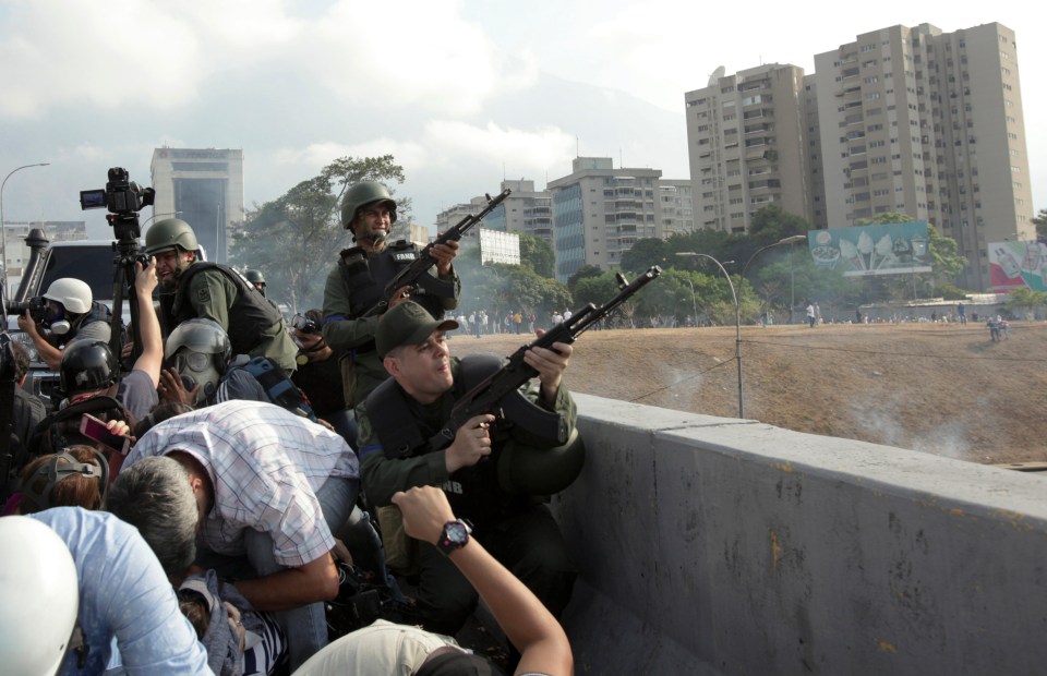  Rebel troops fire their weapons from an overpass outside La Carlota military airbase where loyal troops are located