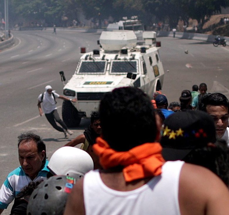  An opposition demonstrator runs before being struck near the Generalisimo Francisco de Miranda Airbase 'La Carlota' in Caracas