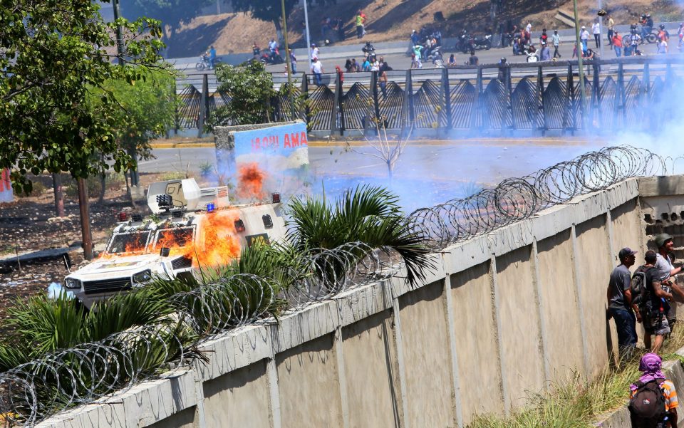  Demonstrators throw petrol bombs to military forces at the air force base La Carlota