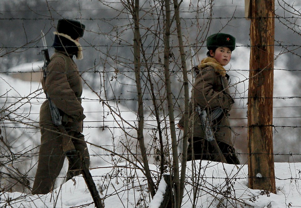  A North Korean female soldier looks back as she and another patrol on a pathway along the bank of the Yalu River