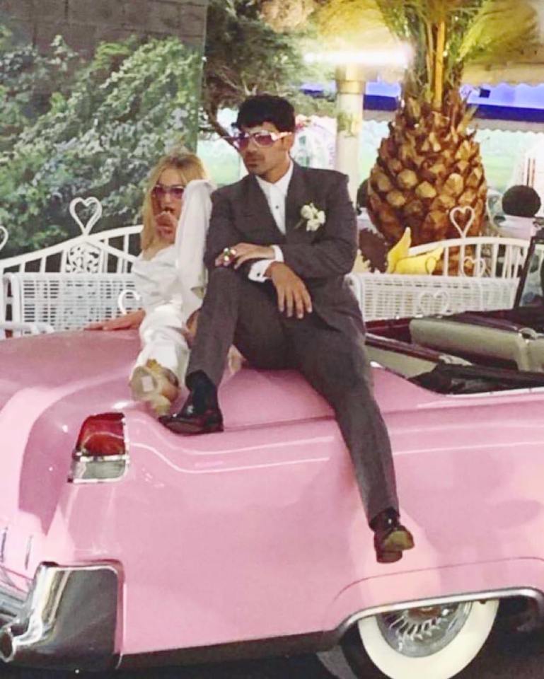  Newlyweds Sophie and Joe posed together on a pink Cadillac car