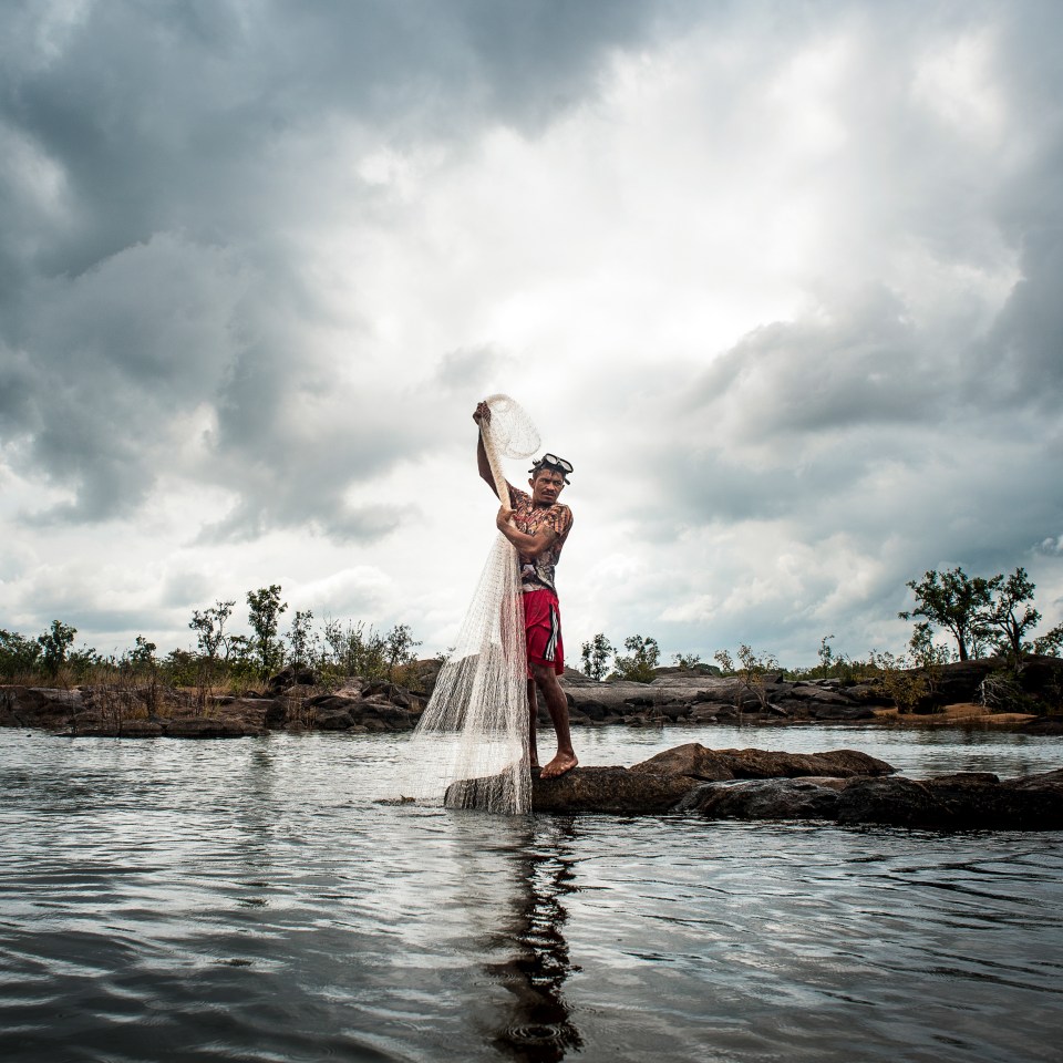  A man pulls and empty net from the water as he desperately fishes