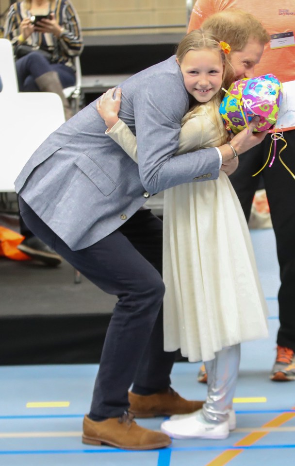  Prince Harry hugs a little girl, Daimy Gommers, who gave him a present for his son