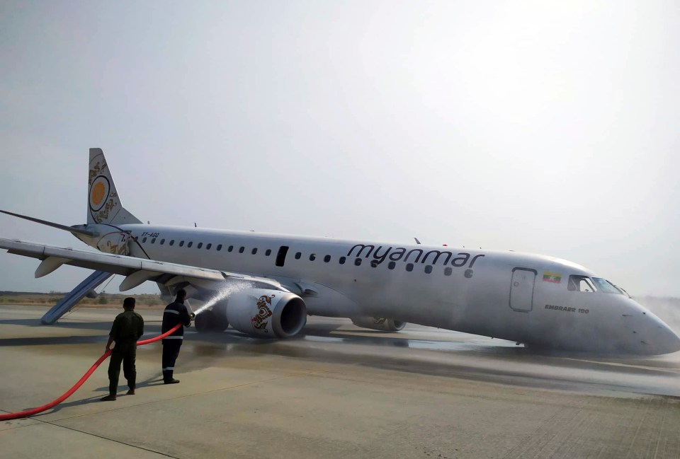 Firefighters work with hose on a plane of Myanmar National Airline (MNA) after an accident at Mandalay International airport today