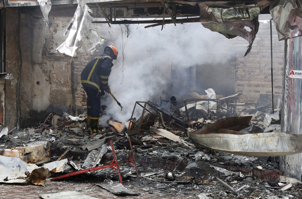  A fireman examines the wreckage of a shop set ablaze by the mob