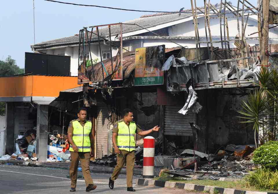  Sri Lankan police officers look at a damaged shop after a mob attack in Minuwangoda