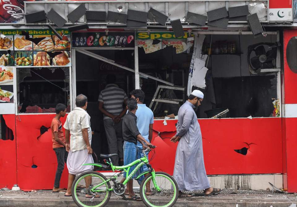  People view a damaged shop in Minuwangoda after a mob attack