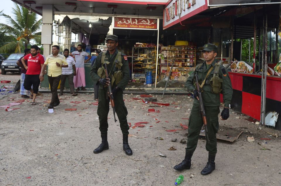  Soldiers standing guard by a damaged shop in Minuwangoda