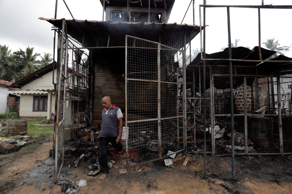  A Muslim man walks next to his burnt shop after a mob attack in Kottampitiya